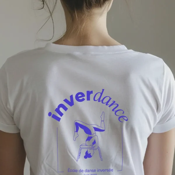 Logo complet de la marque inverdance : en haut la danseuse inversée sur son tabouret, le nom inverdance avec le copyright et la mention école de danse inversée, estd. 2022 en violet sur un t-shirt blanc
